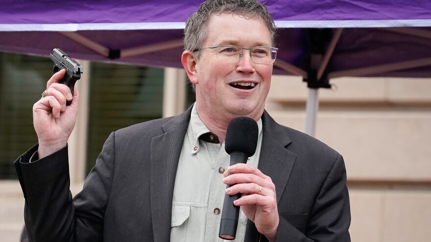 Rep. Thomas Massie, R-Ky., is facing a backlash after posting a photo showing him and his family holding guns in front of a Christmas tree. He's seen here drawing a handgun from his pocket during a pro-gun rally in Frankfort on Jan. 31, 2020.