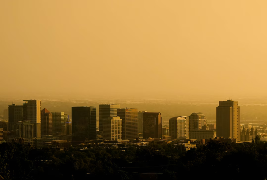 The Salt Lake City skyline veiled in smoke. The air appears yellow as the sun sets. 