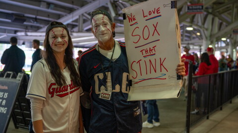 Fans in makeup with a sign that reads "We love sox that stink."