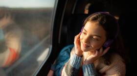 A woman uses headphones while traveling. (Getty Images)