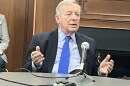U.S. Senator Dick Durbin sitting at a round table with a microphone on it. His shirt is light blue. His tie is vibrant cerulean. 