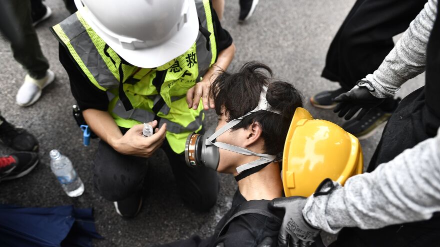 A protester helps a fellow demonstrator after police fired tear gas in the district of Yuen Long in Hong Kong on Saturday. Demonstrators defied a police ban to rally.