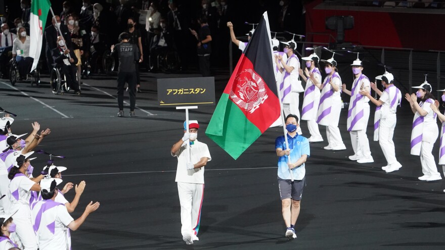 The flag of Afghanistan is presented by volunteers at the Paralympics.