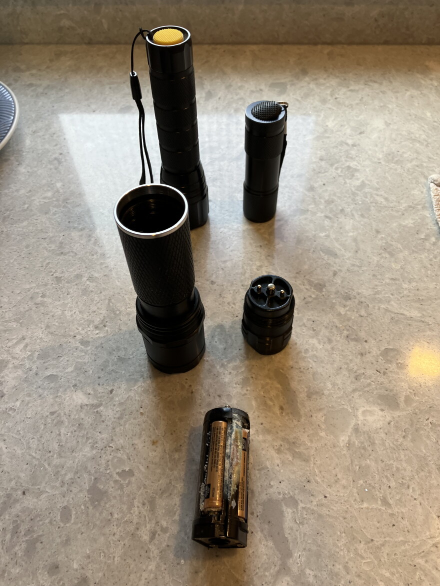 Leaked batteries sit beside an open flashlight.
