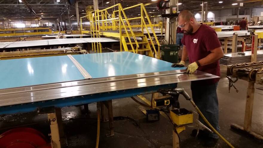 A Wabash National worker slides a partially finished trailer wall onto his station for riveting.