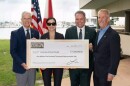 Four people standing behind a large check, smiling.