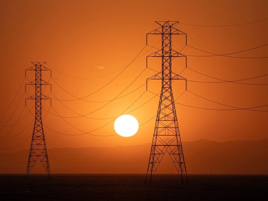 The sun sets behind a row of electric towers in Fresno County on Sept. 6, 2022.