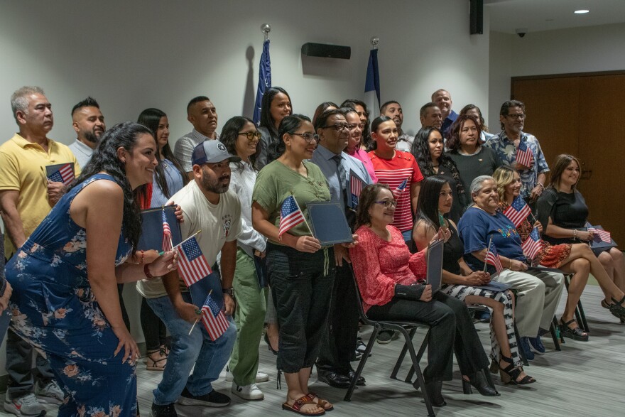 Participants pose with U.S. flags at PATH to Citizenship graduation at the Weber County Main Library in Ogden, May 28, 2025.