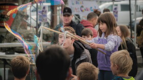 Kids got a chance to play at various booths supervised by nonprofits, like this young girl blowing bubbles bigger than she is, September 9, 2023. (Brian Venua/KMXT)