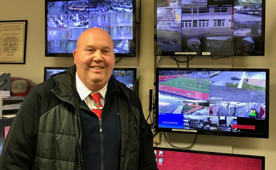 Altoona Area High School Police Services Director Bill Pfeffer stands in front of the school's banks of security cameras.