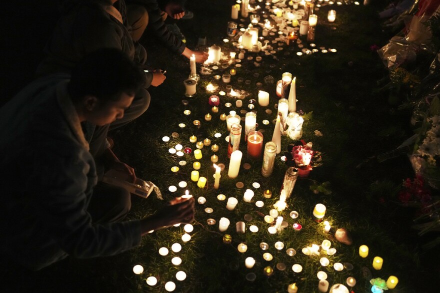 Wendell Gomez, left, places a candle at a memorial for victims after a vehicle drove into a crowd during a Filipino heritage festival in Vancouver, British Columbia, Monday, April 28, 2025.