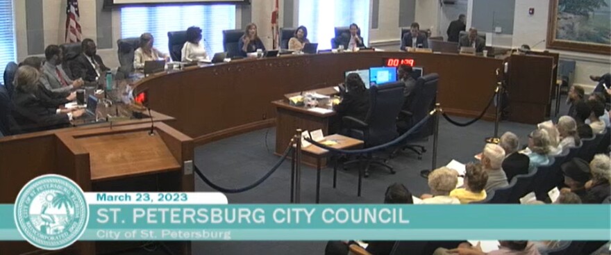 Screen capture of a group of city councilors sitting at a dias, a large crowd sits in chairs on the other side of a rope line. At the bottom of the screen, a banner reads "March 23, 2023 St. Petersburg City Council."