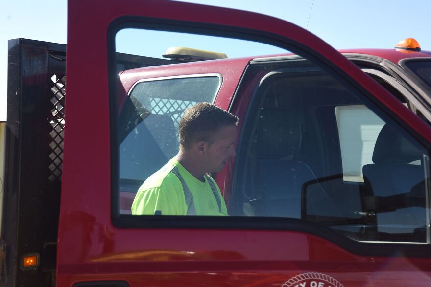 A man stands in an open door of a red pickup truck