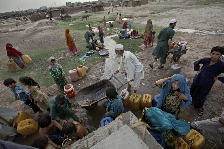 Afghan refugees collect water from a water point in a slum area on the outskirts of Islamabad, in May.