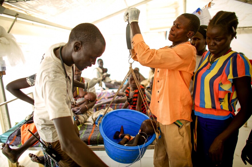 Local nurses at the MSF facility weigh a baby girl in a ward for malnourished children.