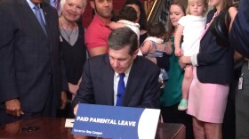 Gov. Roy Cooper, at a ceremony held at the governor's mansion, on Thursday, signs an executive order extending full paid parental leave to state employees at cabinet agencies.