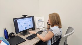 Woman sits at a desk while talking on the phone. 