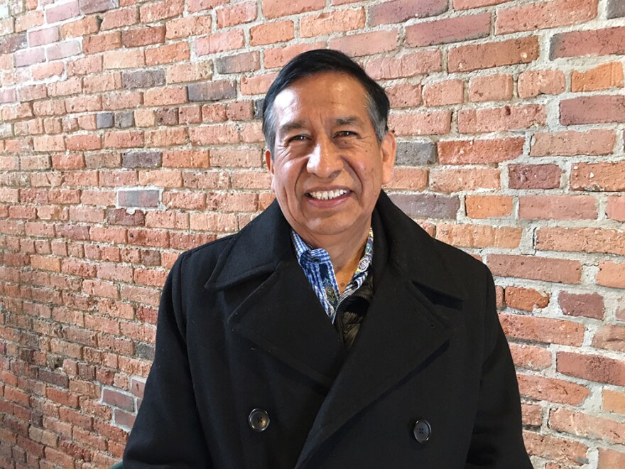 adrian iraola stands in front of brick wall