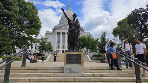 A picture of the Wisconsin Capitol and the "Forward" statue in front of it, a bronze allegorical figure of a woman symbolizing progress, created by Jean Pond Miner for the 1893 World's Fair, representing women's suffrage and the state's motto.