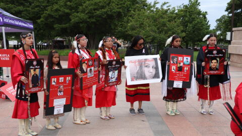 Young women hold signs of victims of the Missing and Murdered Indigenous People's Crisis near the steps of the OK Capitol