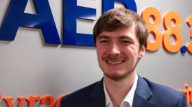 Photo of WAER Alex Grondin standing at station's marquee wall