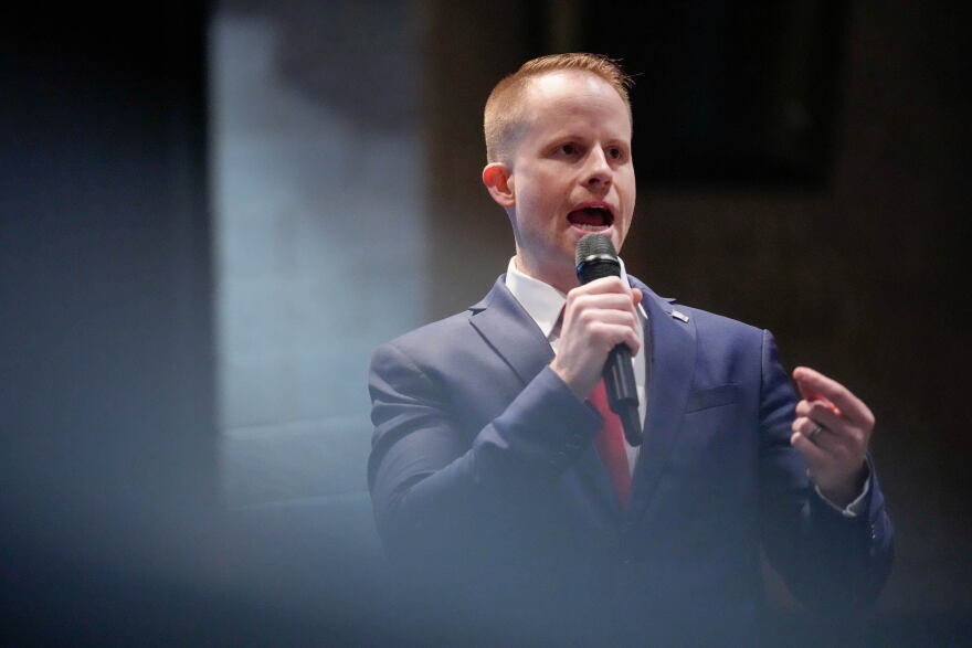 A man in a suit speaks into a microphone.