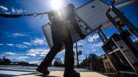 A technician removes a solar panel from a lift  during a solar panel installation on the rooftop of Boston Building Resources in Jamaica Plain.