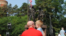 A man kneels beside his son after placing small flags at the base of the monument following the Memorial Day ceremony in 2012.