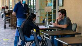 Alonso Escalante, 33, a waiter at Ghee Indian Kitchen, takes down an order from guests visiting the restaurant in Dadeland on Wednesday, May 20, 2020. Niven Patel, the owner of Ghee, is starting to accept guests inside his restaurant a few days after Miami-Dade County entered the first phase of reopening during the COVID-19 crisis.