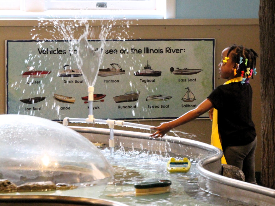 A child plays with a fountain at a children's museum.