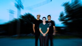 Three people stand outside with a blank expression with a blurring effect around them.