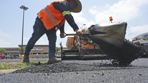 A man shovels hot asphalt during a parking lot