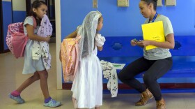 Attendance Clerk Katrice Grant speaks to siblings Melanie Pacheco, 8, left, and Marilynn Pacheco, 5, in the hallway before heading to their classrooms, Tuesday, Oct. 1, 2024, at Algodones Elementary School in Algodones, N.M. (AP Photo/Roberto E. Rosales)