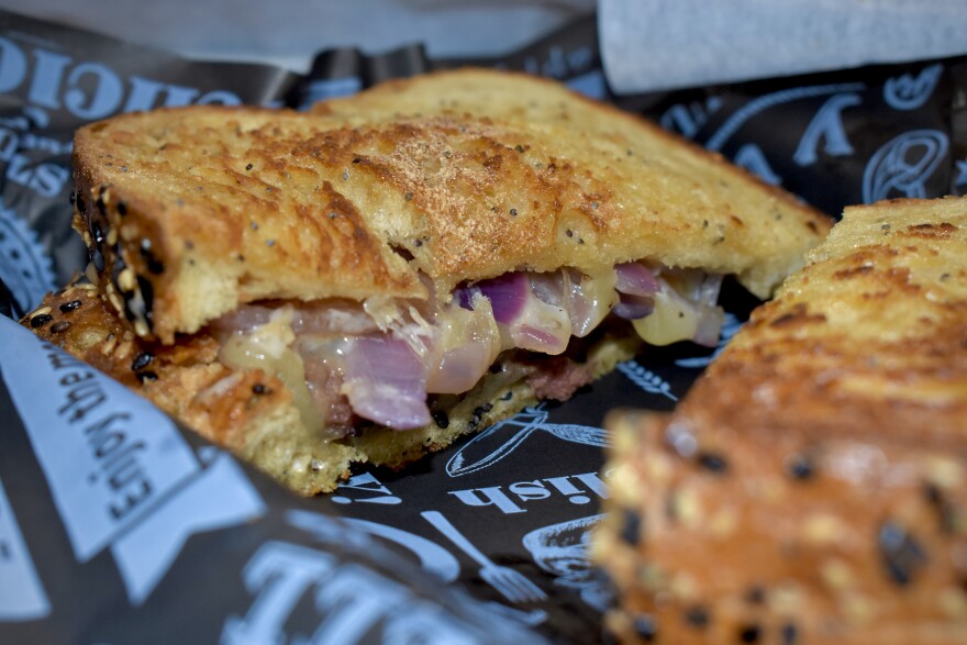 A sandwich with toasted bread and red onions is cut in half.