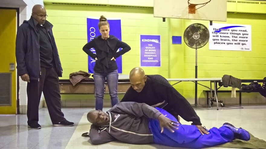 Neighbors learn how to move gunshot victims safely. Temple emergency department nurse Oscar Hankinson, Jr., acts as the victim, while emergency department nurse Kayne Puchon looks on.