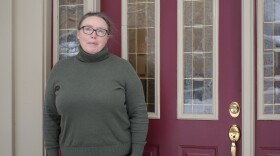 A woman stands outside of her Anchorage home.