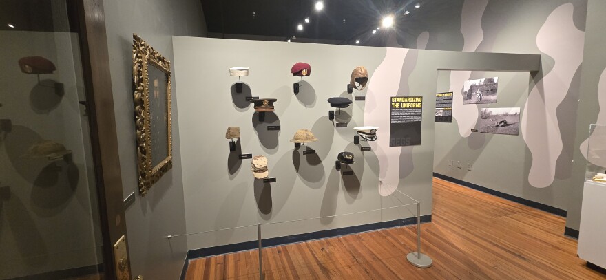 The exhibit "Dressing History: Fabric of War" includes this display of military hats - or covers as they're commonly known - from different eras.