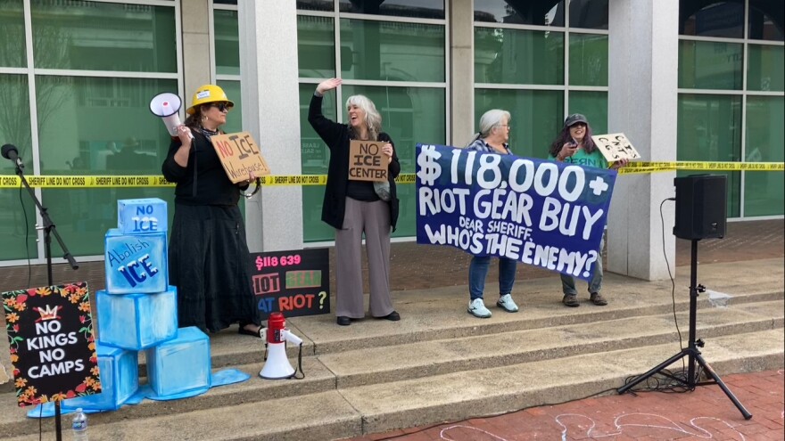 Protestors chant and play music as they protest the purchase of riot gear