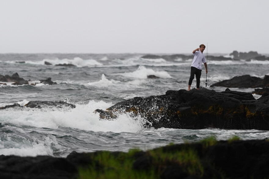 Chase Gabin fishes among the rocks as Hurricane Nolo sits nearby Friday, Sept. 25, 2026, in Hilo, Hawaii. (AP Photo/Gregory Bull)