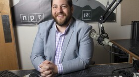 Paul Boger is sitting in the KUNR Studios. He is looking at the camera and smiling.