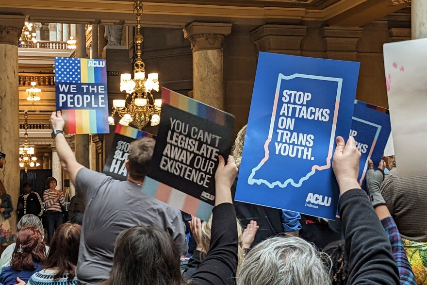 A crowd holds signs at Indiana's 2023 LGBTQ+ Statehouse Day.