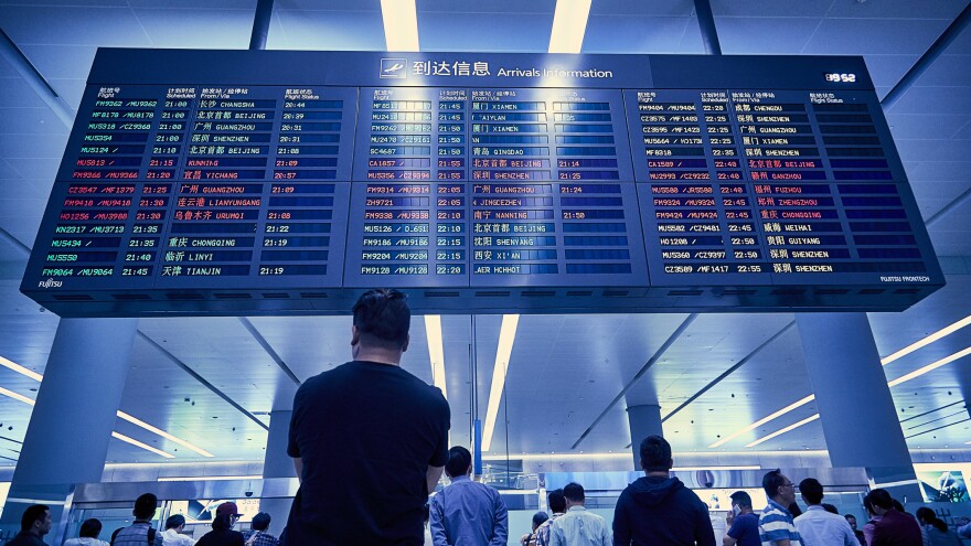 People waiting at an airport arrivals and departure board