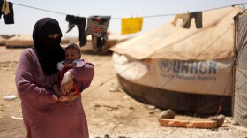 Omm Ahmed, a refugee from Daraa, Syria, carries her infant near her tent at Zaatari Refugee Camp in Mafraq, Jordan, on Sunday. Syrian civilians have borne the greatest brunt of the conflict in their country.