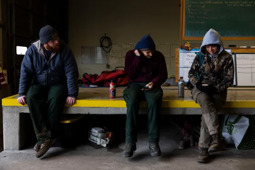 Patrick Monaco, Pen Johnson and Piper Morris look at the fire forecast on their phones before heading to a burn unit early in the morning at their office March 16, 2026, in Carterville, Illinois.