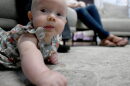 A baby holds its head up while lying on the floor