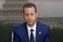 A man in a blue suits looks at the camera