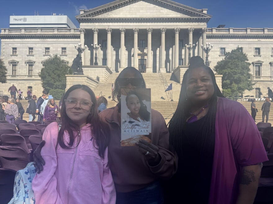 Darlene Stinson holds a program honoring her daughter, Darlisha McIlwain (43), alongside friends at the 2026 Silent Witness Ceremony on the Statehouse grounds in Columbia.