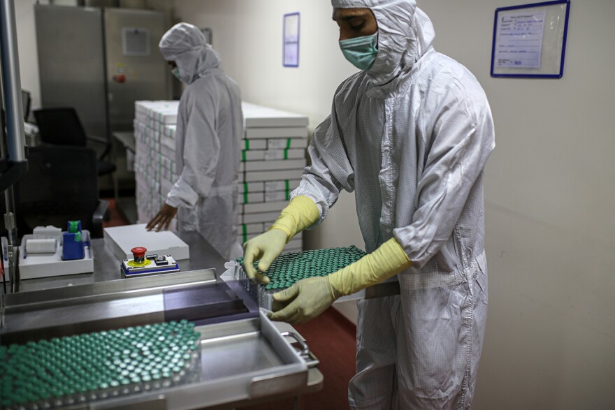 An employee removes vials of the Covid-19 vaccine developed by AstraZeneca and the University of Oxford from a machine on the production line at the Serum Institute of India Hadaspar plant in Pune, Maharashtra, India. [Dhiraj Singh / Bloomberg via Getty Images]