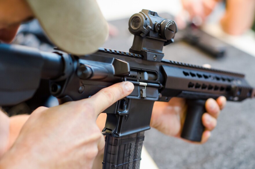  A man holding an AR-style rifle.