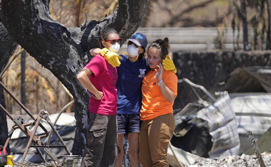 Women hug after digging through rubble of a home destroyed by a wildfire on Friday, Aug. 11, 2023, in Lahaina, Hawaiʻi. (AP Photo/Rick Bowmer)
